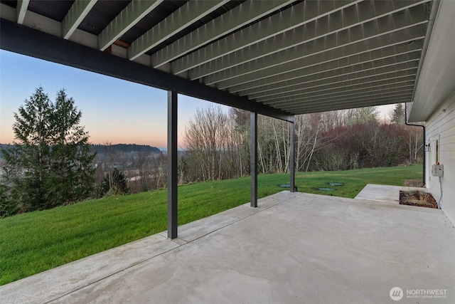 patio terrace at dusk featuring a yard