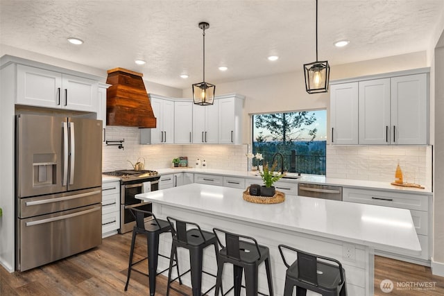 kitchen featuring premium range hood, pendant lighting, stainless steel appliances, and a center island