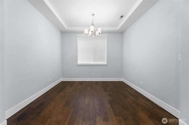 spare room featuring visible vents, baseboards, a tray ceiling, and dark wood-style flooring