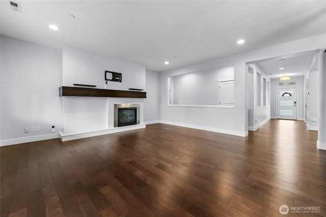 unfurnished living room featuring recessed lighting, visible vents, dark wood-type flooring, and a glass covered fireplace