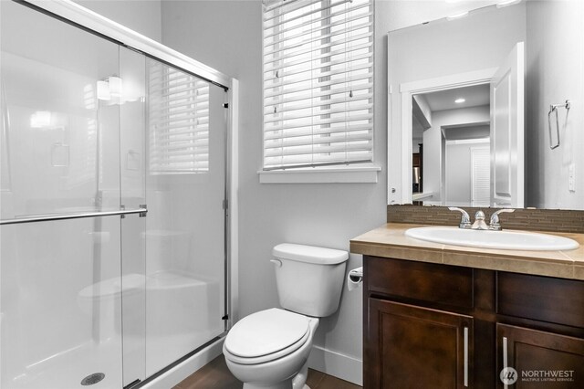 bathroom featuring vanity, a shower stall, toilet, and baseboards