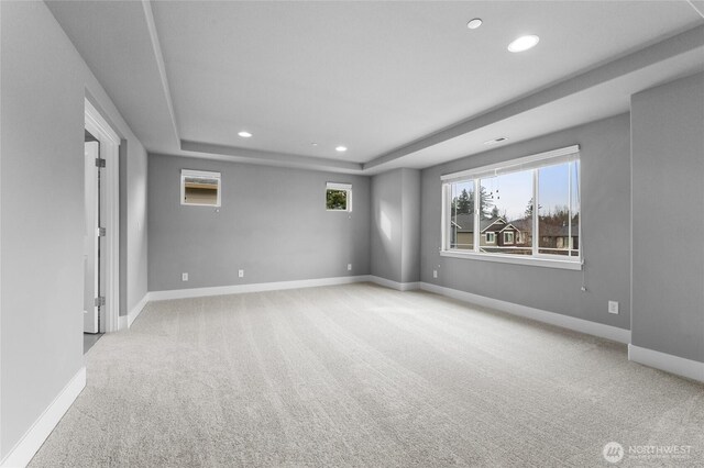 carpeted empty room featuring a tray ceiling, recessed lighting, and baseboards