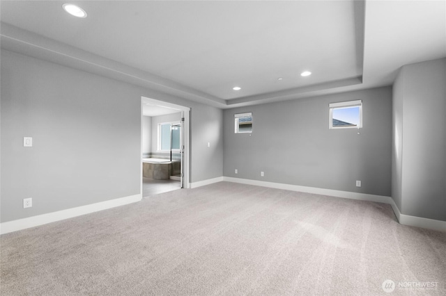 interior space featuring light carpet, recessed lighting, a raised ceiling, and baseboards