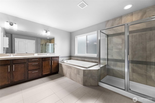 bathroom featuring tile patterned flooring, visible vents, a shower stall, a garden tub, and double vanity