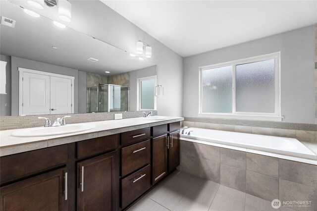 full bathroom with a shower stall, a bath, double vanity, and a sink