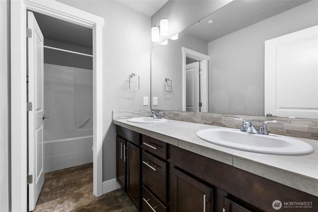 full bath featuring double vanity, bathing tub / shower combination, baseboards, and a sink