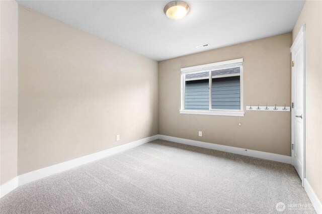 carpeted empty room featuring visible vents and baseboards