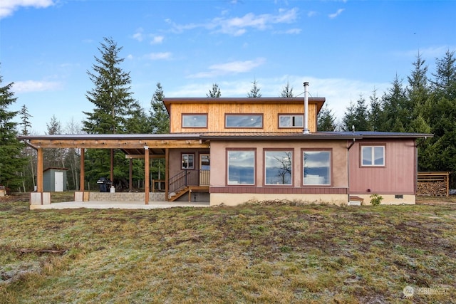 back of property with a patio, a lawn, and a storage unit