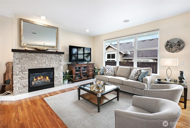 living area with a stone fireplace and wood finished floors