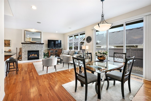 dining room with light wood finished floors, visible vents, recessed lighting, and a fireplace