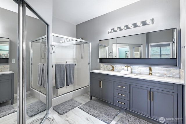 bathroom with double vanity, a shower stall, marble finish floor, and a sink