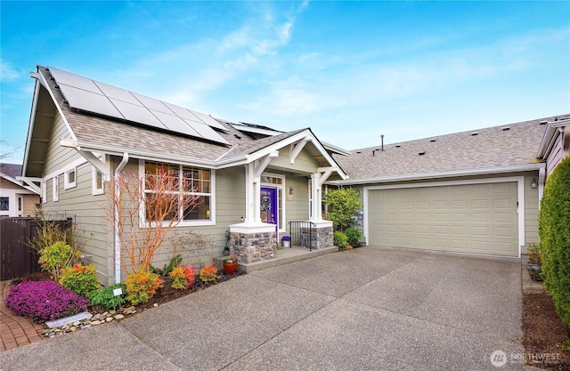 view of front of property with fence, a garage, roof mounted solar panels, and a shingled roof