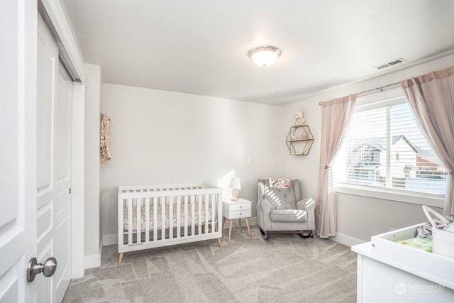 carpeted bedroom featuring a closet and a crib