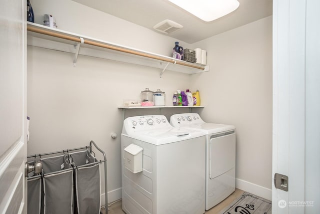 clothes washing area featuring light hardwood / wood-style floors and washer and dryer