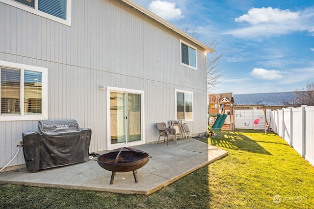 rear view of property with a yard, a patio area, a playground, and an outdoor fire pit