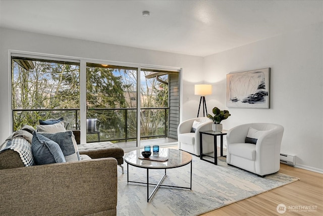 living area with baseboards, a baseboard heating unit, and wood finished floors