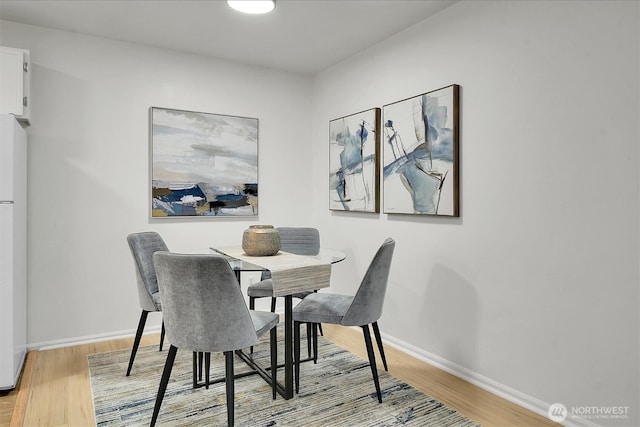 dining area with baseboards and light wood-style floors