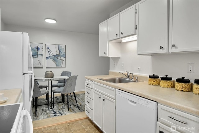 kitchen featuring a sink, white appliances, white cabinets, and light countertops