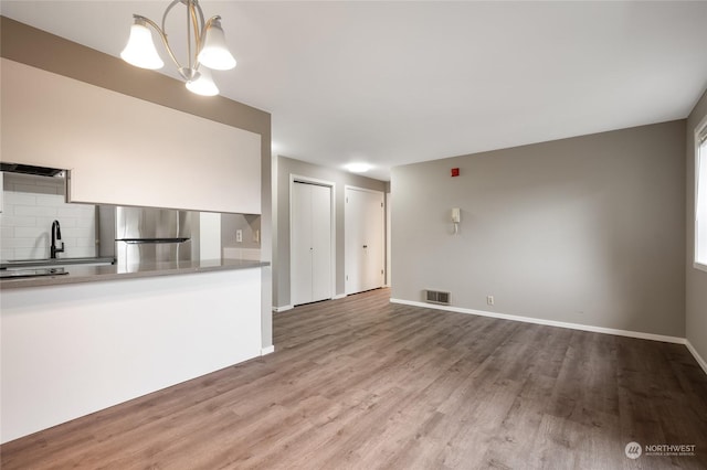 unfurnished living room featuring hardwood / wood-style flooring, a chandelier, and sink