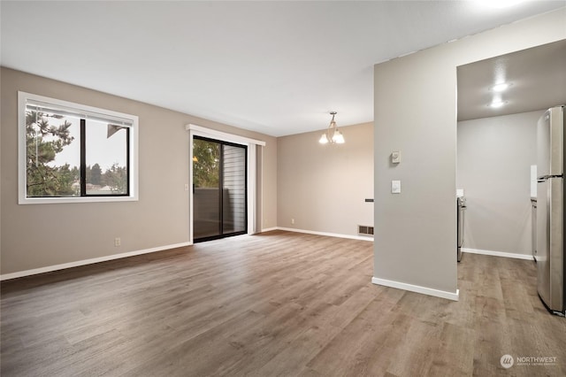 spare room featuring a notable chandelier and light hardwood / wood-style flooring