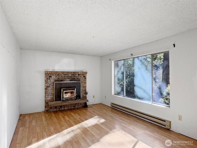 unfurnished living room with a baseboard radiator, a brick fireplace, wood-type flooring, and a textured ceiling