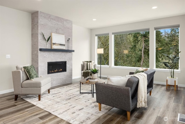 living room featuring a tiled fireplace, hardwood / wood-style floors, and a healthy amount of sunlight