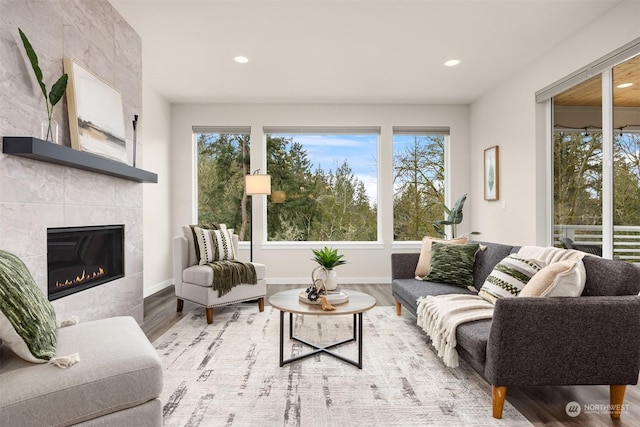 living room with a tile fireplace, plenty of natural light, and light wood-type flooring