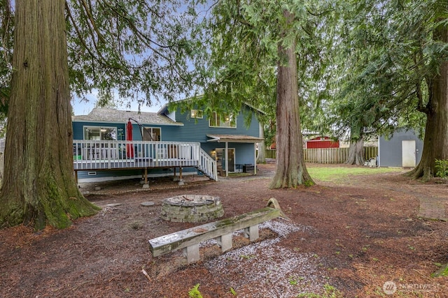 rear view of property with a wooden deck, a fire pit, and a storage shed