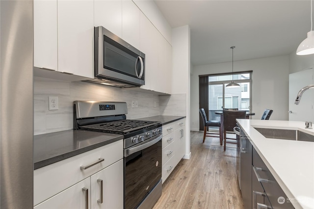 kitchen featuring hanging light fixtures, white cabinets, and appliances with stainless steel finishes