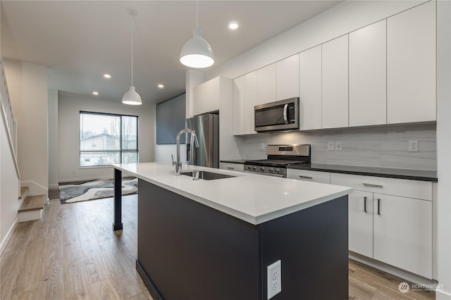 kitchen featuring tasteful backsplash, appliances with stainless steel finishes, a kitchen island with sink, and hanging light fixtures