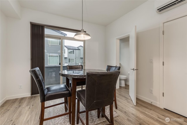 dining area with a wall mounted air conditioner and light wood-type flooring