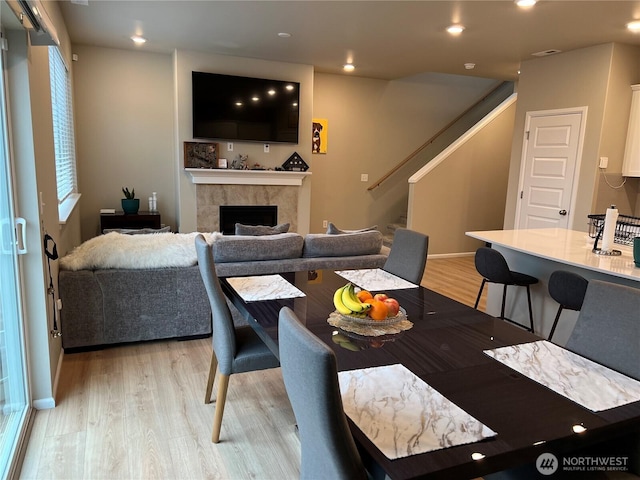 dining room with a tiled fireplace and light wood-type flooring