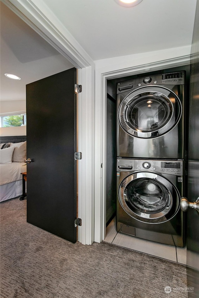 laundry area featuring stacked washer and dryer and light carpet