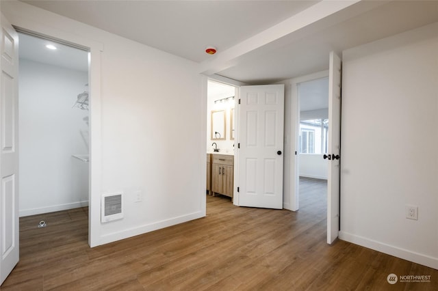 unfurnished bedroom with ensuite bathroom, sink, and hardwood / wood-style floors