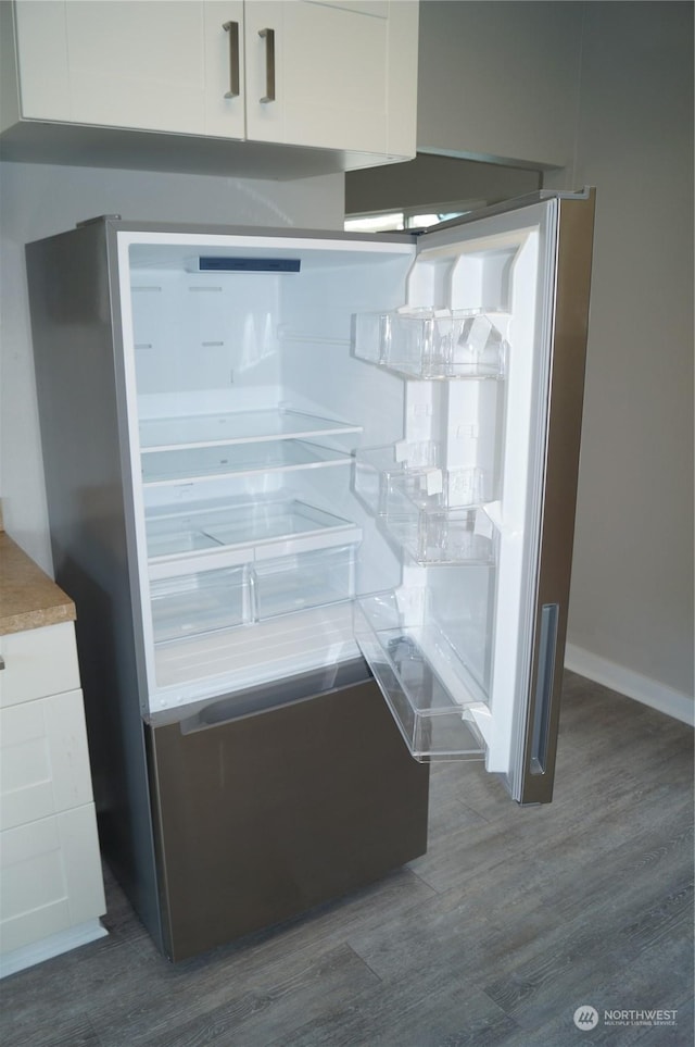 details with dark wood-type flooring, white cabinets, and stainless steel refrigerator