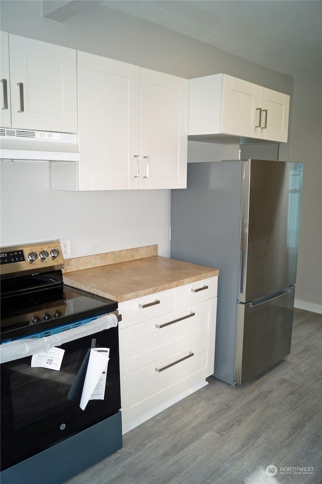 kitchen with stainless steel appliances, white cabinets, and light wood-type flooring