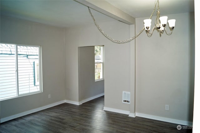 empty room with dark wood-type flooring and a chandelier