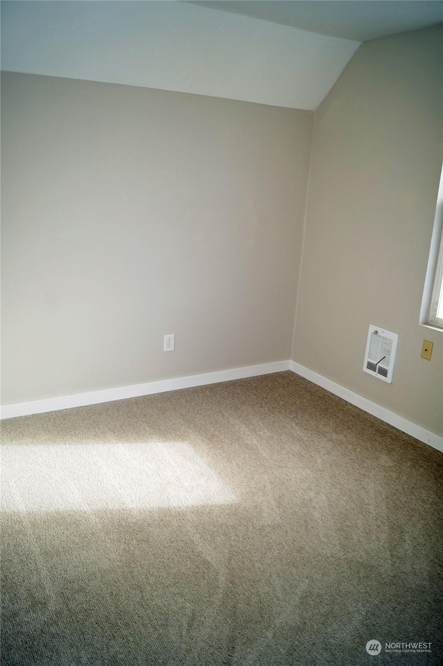 empty room featuring vaulted ceiling and carpet flooring