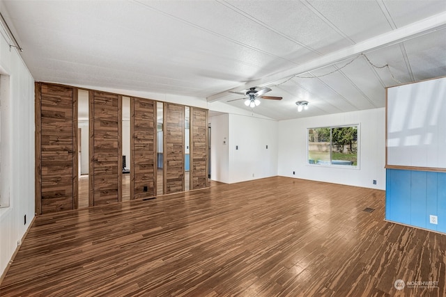 unfurnished living room with lofted ceiling, wooden walls, hardwood / wood-style floors, and ceiling fan