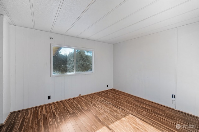 empty room with wood-type flooring and a textured ceiling