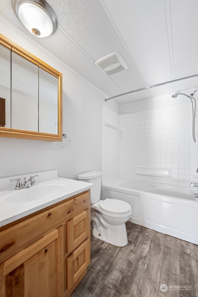 full bathroom featuring wood-type flooring, shower / bath combination, vanity, toilet, and a textured ceiling