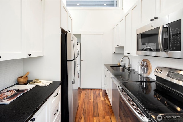 kitchen featuring stainless steel appliances, sink, white cabinets, dark hardwood / wood-style floors, and decorative backsplash