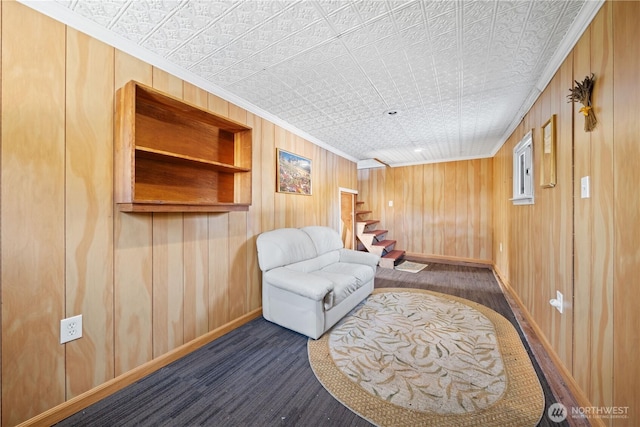 living area with ornamental molding and wood walls