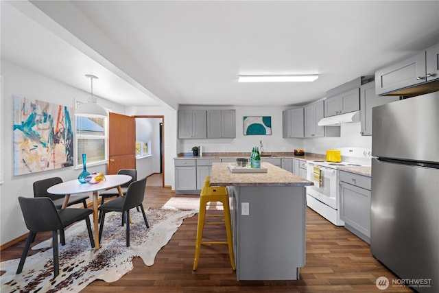 kitchen with a kitchen island, a breakfast bar, white electric range, decorative light fixtures, and stainless steel fridge