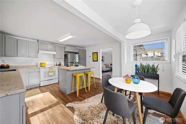 kitchen featuring sink, gray cabinetry, stainless steel refrigerator, a kitchen island, and electric stove