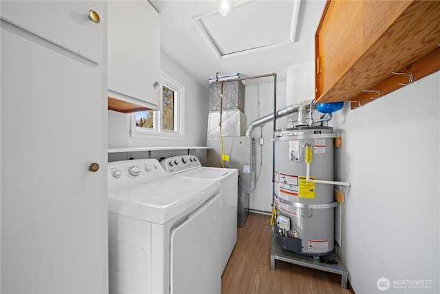 laundry room with light hardwood / wood-style flooring, strapped water heater, washer and clothes dryer, and cabinets