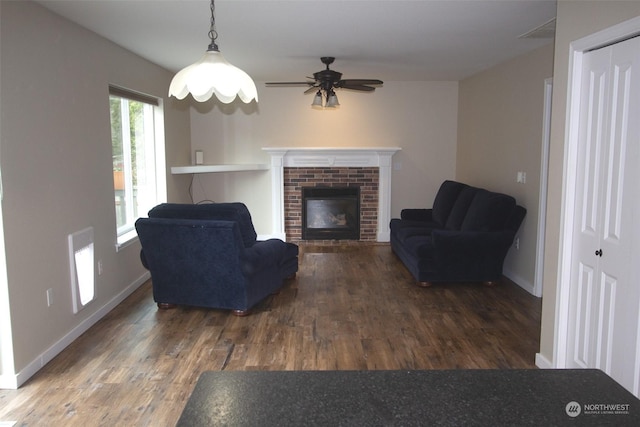 living room featuring a brick fireplace and dark wood-type flooring