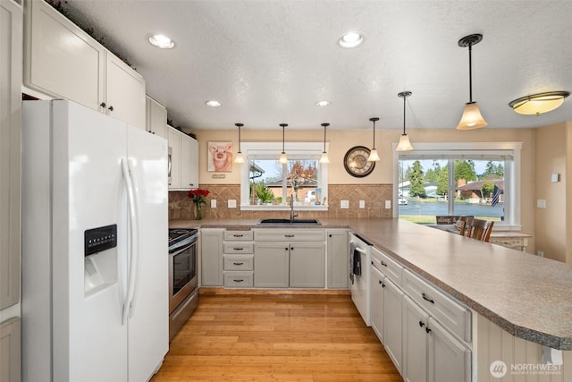 kitchen with pendant lighting, stainless steel electric stove, a sink, white fridge with ice dispenser, and a peninsula