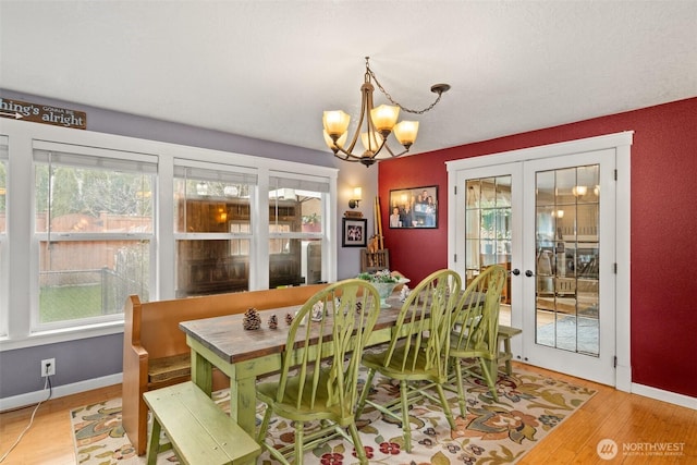 dining area with a chandelier, french doors, baseboards, and wood finished floors