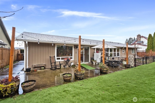 back of property featuring a patio, a lawn, fence, and roof with shingles